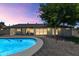 Backyard oasis featuring a sparkling pool, brick patio, lush lawn, and mature landscaping under a dusky sky at 9450 N 83Rd Pl, Scottsdale, AZ 85258