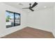 Minimalist bedroom with a modern ceiling fan, hardwood flooring, large window with views of lush greenery at 9450 N 83Rd Pl, Scottsdale, AZ 85258