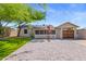 Landscaped backyard with covered patio and brick pavers, lush lawn, mature tree, and a detached garage at 9520 N Central Ave, Phoenix, AZ 85020