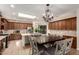 Open kitchen features wooden cabinets, tile backsplash, stainless steel appliances, island, and dining table with chandelier at 10449 E Jacob Ave, Mesa, AZ 85209