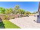 Large paver patio with a grill station and outdoor fireplace bordered with lush desert landscaping at 10664 E Ellis St, Mesa, AZ 85207