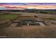 Stunning aerial view of property featuring modern farmhouse and spacious land, set against a vibrant sunset backdrop at 11564 E Windsor Way, Florence, AZ 85132