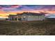 Modern home boasts a sleek design, highlighted by stucco, black trim, and a durable metal roof against a colorful sky at 11564 E Windsor Way, Florence, AZ 85132