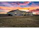 Modern white stucco home with black trim and a metal roof, enhanced by a vibrant sunset, providing a captivating view at 11564 E Windsor Way, Florence, AZ 85132