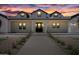 Beautiful white farmhouse with black accents, dormer windows, and landscape lighting at sunset at 11564 E Windsor Way, Florence, AZ 85132