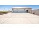 A long concrete driveway leading to a garage with white doors and a metal roof at 11564 E Windsor Way, Florence, AZ 85132