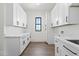 Bright laundry room with white cabinetry, quartz countertops, and a window view at 11564 E Windsor Way, Florence, AZ 85132