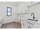 Well-lit laundry room featuring white cabinets, modern fixtures, and a convenient sink area at 11564 E Windsor Way, Florence, AZ 85132