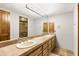 Bathroom featuring a double sink vanity, a large framed mirror, wooden cabinets, and a glass shower at 11773 E Desert Trail Rd, Scottsdale, AZ 85259