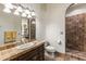 Well-lit bathroom with a decorative mirror, vanity, and custom-tiled walk-in shower at 11773 E Desert Trail Rd, Scottsdale, AZ 85259