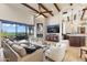 Bright living room features stone fireplace, wooden beams, and large glass doors leading to an outdoor patio with desert views at 11773 E Desert Trail Rd, Scottsdale, AZ 85259