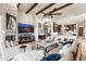 Spacious living room with stone fireplace and wooden beams with a mounted tv, open to kitchen area at 11773 E Desert Trail Rd, Scottsdale, AZ 85259