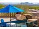Poolside lounge area featuring a blue umbrella for shade, a small table, and scenic desert views at 11773 E Desert Trail Rd, Scottsdale, AZ 85259