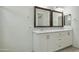 Bright bathroom featuring a double sink vanity with granite countertops, framed mirrors, and white cabinets at 14844 W Pershing St, Surprise, AZ 85379