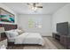 Staged bedroom featuring a tufted headboard, wall-mounted TV, ceiling fan, and bright natural light at 14844 W Pershing St, Surprise, AZ 85379