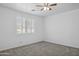 Clean, empty bedroom with carpet, a ceiling fan, plantation shutters, and bright natural light at 14844 W Pershing St, Surprise, AZ 85379