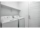 Well-lit laundry room with side-by-side washer and dryer with shelving at 14844 W Pershing St, Surprise, AZ 85379
