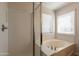 Bright bathroom features a shower and bathtub combo with natural light from the windows at 18123 W Lundberg St, Surprise, AZ 85388