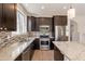 Kitchen boasts stainless appliances, granite counters, tile backsplash, sink under window and dark wood cabinets at 18123 W Lundberg St, Surprise, AZ 85388