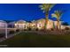 Charming single-story home with a three-car garage, desert landscaping, and illuminated palm trees at dusk at 20151 E Via Del Palo St, Queen Creek, AZ 85142