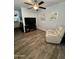 Living room with wood-look floors, ceiling fan, a TV, artwork on the walls, and a white recliner for relaxation at 2715 E Canyon Creek Dr, Gilbert, AZ 85295