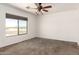 Bedroom features neutral carpet, a ceiling fan, and a large window for ample natural light at 31515 W Buchanan St, Buckeye, AZ 85326