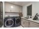 Laundry room featuring front loading washer and dryer units with storage cabinets and sink at 41576 N 107Th Way, Scottsdale, AZ 85262