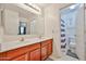 Dual-sink bathroom vanity with wood cabinets and a door opening to a room with a toilet and shower at 4318 W Apollo Rd, Laveen, AZ 85339