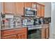 Close-up of the kitchen area with stainless steel appliances, wooden cabinets, and tiled backsplash at 4318 W Apollo Rd, Laveen, AZ 85339