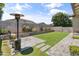 This backyard showcases a spacious lawn, gray paver patio and walkway, mature landscaping, and block fence, perfect for outdoor activities at 455 W Evergreen Pear Ave, Queen Creek, AZ 85140