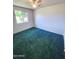 Bright bedroom with plush green carpeting, a ceiling fan, and a large window at 5016 W Sunrise Dr, Laveen, AZ 85339
