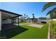 A backyard with a covered patio, pergola, artificial grass, outdoor kitchen, and landscaping at 5259 E Karen Dr, Scottsdale, AZ 85254