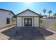 Charming exterior featuring a paved walkway, white paint and dark trim, complemented by lush surroundings and palm trees at 5259 E Karen Dr, Scottsdale, AZ 85254