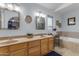 Bright bathroom with dual sinks, framed mirrors, updated lighting, and a separate soaking tub at 5930 E Fountain St, Mesa, AZ 85205