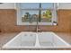 Close-up of a kitchen sink showcasing modern faucet and tiled backsplash, with a view to the backyard at 5930 E Fountain St, Mesa, AZ 85205