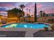 Backyard features a sparkling pool with a waterfall feature and lounge area under festive string lights at dusk at 5930 E Fountain St, Mesa, AZ 85205