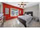 Serene bedroom featuring a queen bed, a red accent wall, and a large window, creating a relaxing and stylish retreat at 7132 W Vermont Ave, Glendale, AZ 85303