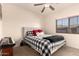 Bright bedroom featuring a ceiling fan, a window, and a comfy bed with a decorative checkered pattern at 7726 E Baseline Rd # 154, Mesa, AZ 85209