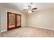 Spacious carpeted bedroom with ceiling fan, French doors, and neutral color scheme at 119 E Palomino Dr, Tempe, AZ 85284
