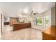 Spacious living room with travertine floors, ceiling fan, pool views, and expansive kitchen island seating at 119 E Palomino Dr, Tempe, AZ 85284