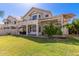 Expansive backyard featuring a covered patio, outdoor dining, lush green grass, and mature trees at 1343 E Amberwood Dr, Phoenix, AZ 85048