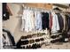 View of a fully stocked primary closet with hanging clothes and shelf storage for shoes and baskets above at 1343 E Amberwood Dr, Phoenix, AZ 85048