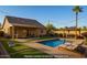 Inviting backyard featuring a refreshing pool, cozy lounge chairs, and a charming outdoor kitchen under festive string lights at 1381 W Gary Dr, Chandler, AZ 85224