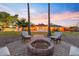Charming fire pit area surrounded by comfortable seating, set against a backdrop of a beautifully lit backyard oasis at 14221 N 43Rd St, Phoenix, AZ 85032