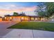 Charming single-story home with a well-manicured lawn and a two-car garage at sunset at 14221 N 43Rd St, Phoenix, AZ 85032