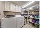 Functional laundry room with washer, dryer, overhead storage, and shelving for supplies at 14221 N 43Rd St, Phoenix, AZ 85032