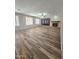 This open-concept living room features wood-look tile flooring, a fireplace and several windows with plantation shutters at 15656 W Desert Mirage Dr, Surprise, AZ 85379