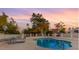 Community pool with a jacuzzi, seating areas and lush greenery, under a sunset sky at 1913 S River Dr, Tempe, AZ 85281