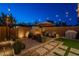 Tranquil backyard featuring a brick fireplace, comfortable seating, ambient lighting, and lush greenery at 1956 W Kinfield Trl, Phoenix, AZ 85085