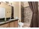 Bathroom with a tan vanity, a toilet, and a tiled stand-up shower with a dark brown curtain at 20332 N Denizen Dr, Surprise, AZ 85387
